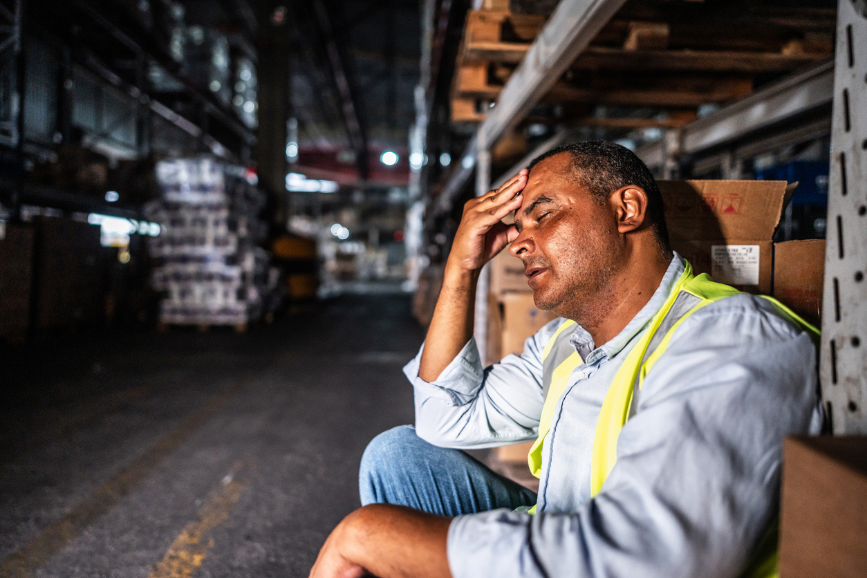 tired mature man sitting at work in a warehouse